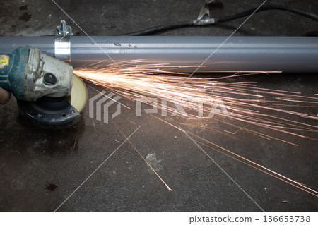 建築工地上,工人使用圓盤砂輪機切割螺栓,火花四濺。 建築工地上,工人使用圓盤砂輪機切割螺栓,火花四濺。 136653738