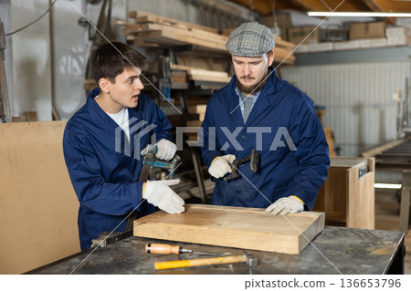 Young men fixing wooden board with clamp Young men fixing wooden board with clamp 136653796