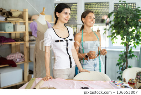 dressmakers are standing in the workshop and smiling dressmakers are standing in the workshop and smiling 136653807