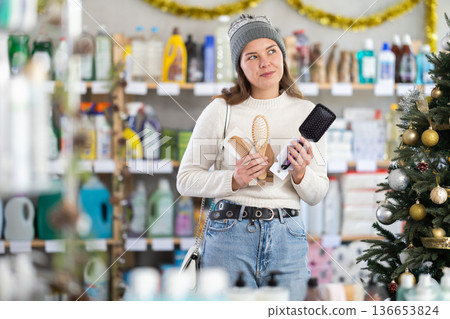 woman chooses a comb against the background of a Christmas tree woman chooses a comb against the background of a Christmas tree 136653824