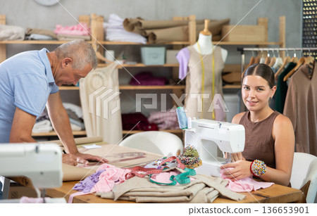 Girl master sew clothes in sewing machine, senior craftsman draw dress pattern Girl master sew clothes in sewing machine, senior craftsman draw dress pattern 136653901