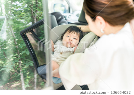 Mother putting baby in car seat Mother putting baby in car seat 136654022