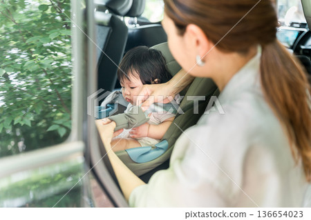 Mother putting baby in car seat 136654023