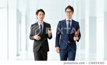 Two male businessmen walking and talking Two male businessmen walking and talking 136654383