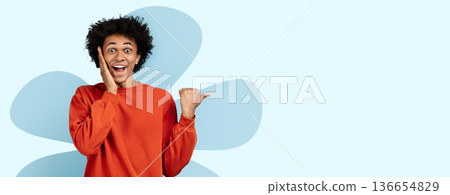 A person with curly hair smiles and gestures with one hand while looking surprised. A light blue background enhances the joyful mood. 136654829