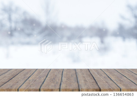 Empty wooden counter table or bench and winter scenery with white snow falling on frozen forest tree Empty wooden counter table or bench and winter scenery with white snow falling on frozen forest tree 136654863