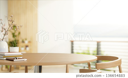 Books and flower vase on round wooden table with chairs across balcony's railing in bright sunlight. Books and flower vase on round wooden table with chairs across balcony's railing in bright sunlight. 136654883