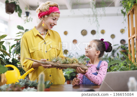 A woman and a young girl share a moment while admiring a display of air plants 136655084