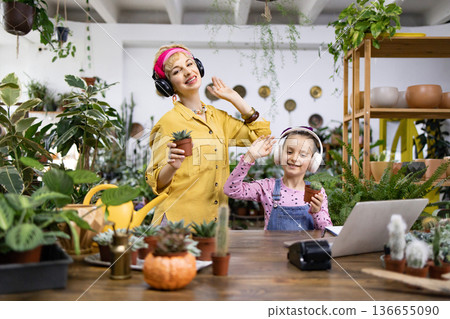 A mother and daughter enjoy their plants while listening to music together, creating a joyful moment A mother and daughter enjoy their plants while listening to music together, creating a joyful moment 136655090