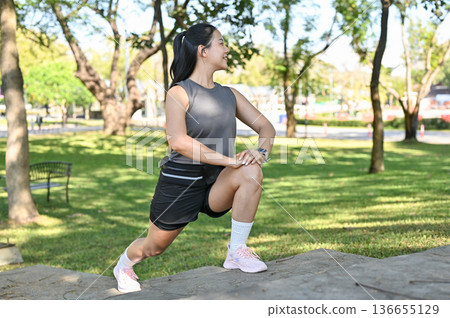 Asian woman in sportswear stretching arms and leg muscles before exercise on concrete stairs in park 136655129