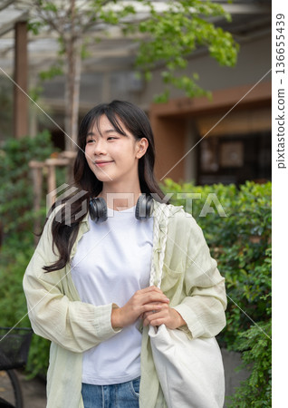 Pretty asian woman tourist standing and holding bag's strap while walking or traveling by local road 136655439
