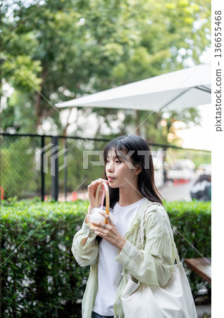 Pretty asian woman tourist holding straw drinking fresh coconut water while standing walking in mall Pretty asian woman tourist holding straw drinking fresh coconut water while standing walking in mall 136655468