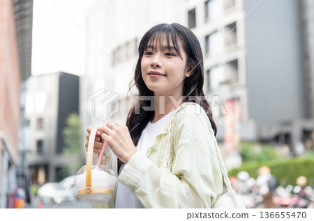 Pretty asian woman tourist holding cup holder with fresh coconut while standing or walking in mall. Pretty asian woman tourist holding cup holder with fresh coconut while standing or walking in mall. 136655470