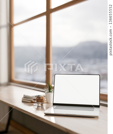 White screen laptop with book and coffee cup on wooden table aside glass wall in living room or cafe 136655552