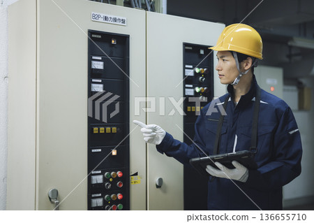 A worker inspecting the electrical equipment of a building with a tablet A worker inspecting the electrical equipment of a building with a tablet 136655710