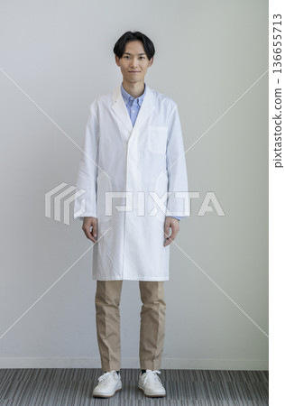 一位三十多歲的男子身穿白大褂，微笑著對著鏡頭，全身照，白色背景，肖像照 136655713