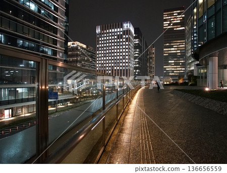 雨夜裡,城市裡濕漉漉的人行道和建築物的燈光 雨夜裡,城市裡濕漉漉的人行道和建築物的燈光 136656559