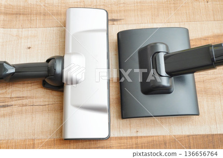 Comparison of vacuum cleaner heads. Home appliances photographed against a wood grain background. Comparison of vacuum cleaner heads. Home appliances photographed against a wood grain background. 136656764