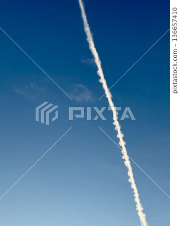 A contrail flying in the blue sky 136657410