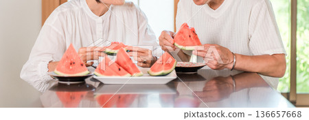 Middle-aged couple, senior, elderly man and woman eating watermelon at the dining table Middle-aged couple, senior, elderly man and woman eating watermelon at the dining table 136657668