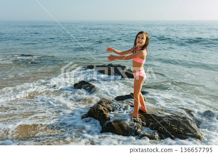 happy small girl standing on the rocky beach happy small girl standing on the rocky beach 136657795