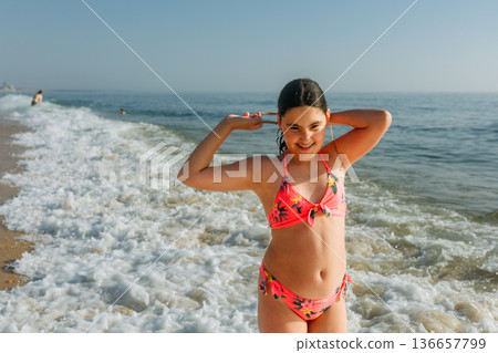 portrait of a teenage girl standing on the beach 136657799