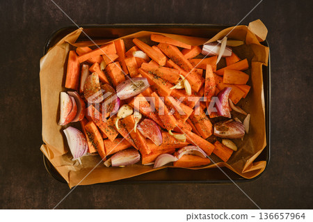 Seasoned sweet potatoes, garlic and onion on tray for healthy home roasting 136657964