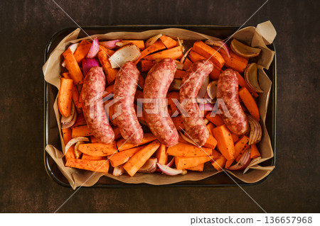 Natural casing sausages with roasted vegetables on a baking tray in a kitchen setting Natural casing sausages with roasted vegetables on a baking tray in a kitchen setting 136657968