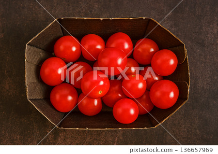 Fresh red tomatoes collected in a basket on a dark surface Fresh red tomatoes collected in a basket on a dark surface 136657969