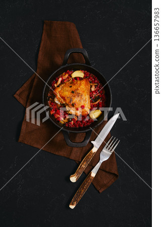 Delicious chicken dish served in a cast iron pot on a dark surface with utensils nearby Delicious chicken dish served in a cast iron pot on a dark surface with utensils nearby 136657983