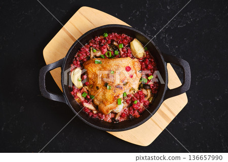 Food dish with chicken and red rice served in a black skillet on a wooden board Food dish with chicken and red rice served in a black skillet on a wooden board 136657990