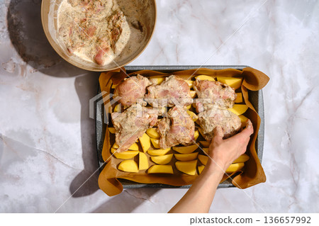 Cooking chicken and potatoes in a kitchen setting with raw ingredients on the counter Cooking chicken and potatoes in a kitchen setting with raw ingredients on the counter 136657992