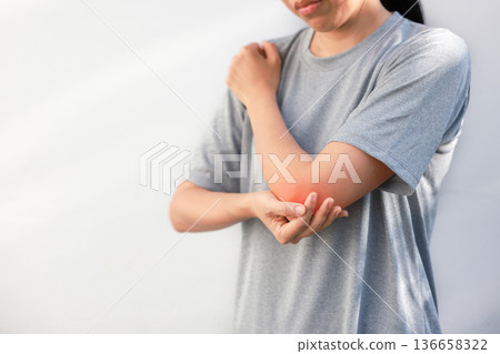 Young woman suffering from acute elbow pain and joint inflammation with red highlight effect, female touching sore arm, tendonitis, sports injury, arthritis, health problem, copy space background. Young woman suffering from acute elbow pain and joint inflammation with red highlight effect, female touching sore arm, tendonitis, sports injury, arthritis, health problem, copy space background. 136658322