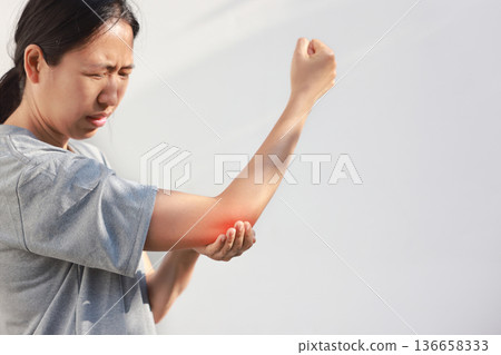 Young woman suffering from acute elbow pain and joint inflammation with red highlight effect, female touching sore arm, tendonitis, sports injury, arthritis, health problem, copy space background. Young woman suffering from acute elbow pain and joint inflammation with red highlight effect, female touching sore arm, tendonitis, sports injury, arthritis, health problem, copy space background. 136658333