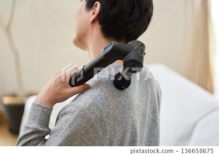 亞洲男子用按摩槍按摩肩膀 136658675