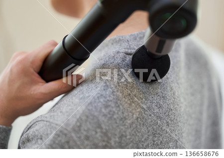 亞洲男子用按摩槍按摩肩膀 136658676