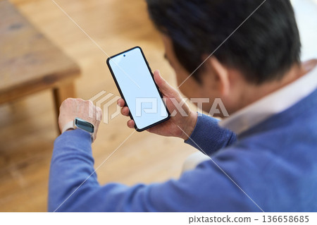 Senior Asian man managing his health with a smart device Senior Asian man managing his health with a smart device 136658685