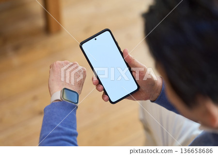 一位年長的亞洲男子使用智慧型裝置管理自己的健康 136658686
