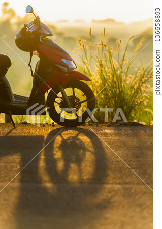 Silhouette of a red scooter in fog at sunrise, atmospheric minimalist landscape with a sense of silence, calm and solitude. High quality photo 136658893
