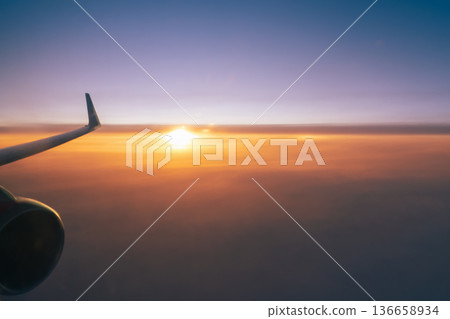 A flying plane over an orange sunset sky, a wing and a turbine in close-up. The concept background of the copy space air travel. High quality photo A flying plane over an orange sunset sky, a wing and a turbine in close-up. The concept background of the copy space air travel. High quality photo 136658934