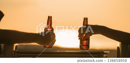 beer bottles in the hands of vacationers, which are held by a couple of lovers or friends. Camping together on the beach and a trip to a warm country for a honeymoon. High quality photo beer bottles in the hands of vacationers, which are held by a couple of lovers or friends. Camping together on the beach and a trip to a warm country for a honeymoon. High quality photo 136658938