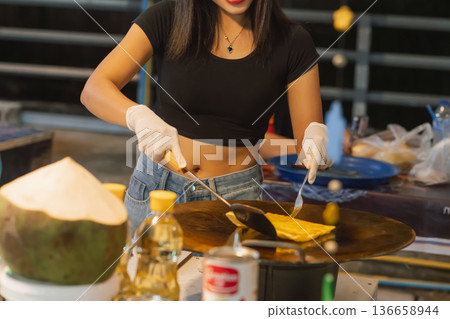 Preparation of pancakes sweet roti at a street stall in Bangkok, showcasing a traditional Thai snack being made by a local vendor in the evening. High quality photo 136658944