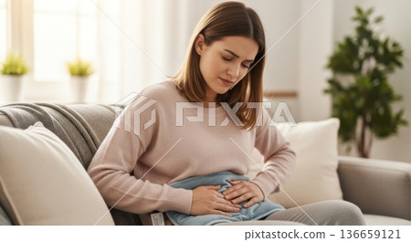 Woman experiencing period cramps using a hot water bottle for relief 136659121