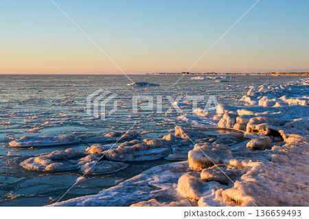 Frozen Baltic Sea Coast at Sunset with Ice Floes and Glowing Winter Light in Latvia, Liepaja Frozen Baltic Sea Coast at Sunset with Ice Floes and Glowing Winter Light in Latvia, Liepaja 136659493