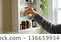 Person reaches for a prescription bottle from a shelf in a home setting during the day 136659934