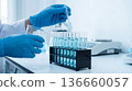 Scientist works in a lab with test tubes and blue liquid during a research experiment in a cleanroom setting 136660057