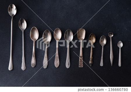 Set of different spoons. Silver cutlery on a black background. Spoon on table Set of different spoons. Silver cutlery on a black background. Spoon on table 136660780