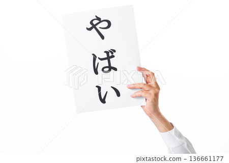 Hand holding a piece of paper with the word "yabai" written on it 136661177
