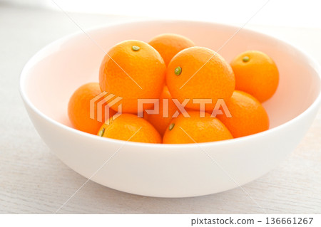 Shining orange kumquats on a white plate Shining orange kumquats on a white plate 136661267