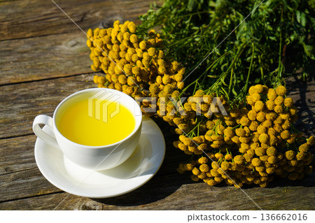 A cozy still life featuring freshly brewed tansy tea in a simple white cup. A natural solution for aiding digestion and easing cramping. 136662016